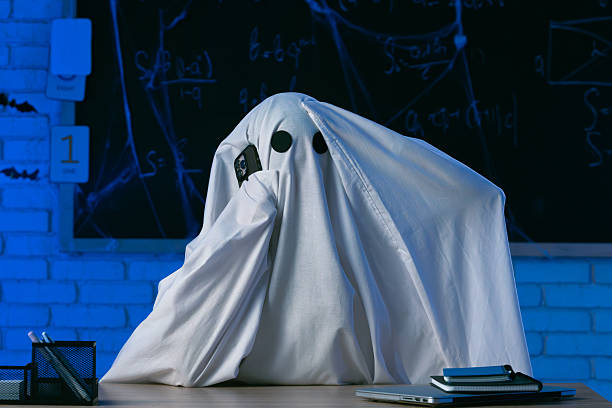 istock A man in a white ghost sheet sits at a table in a blue-lit room, talking on the phone and clutching his head 2237083321