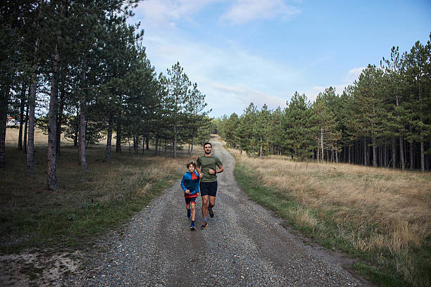 Father and son enjoying a jog on a gravel path, embracing a healthy lifestyle together