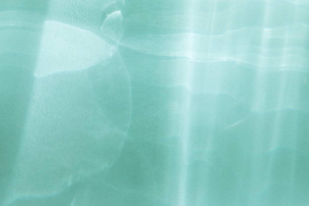 Abstract sunlight shadows turquoise background with flare and glare from glass top view. Natural abstract aesthetic mockup with caustic effects for design and product presentation.