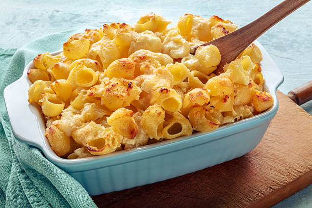 Mac and Cheese, macaroni pasta, oven-baked in a casserole with cream, freshly cooked, on a wooden board