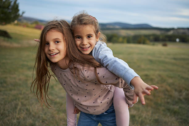 istock Sisters enjoying piggyback ride in a grassy field 2237084287
