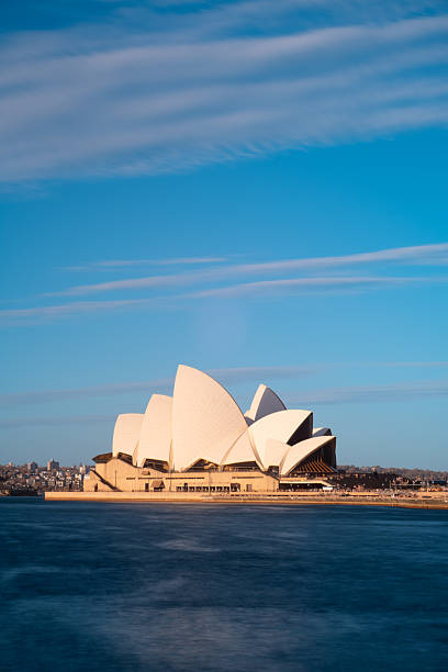 Sydney, Australia - January 3, 2007: Close up of the famous Sydney Opera House roof, showing the "shells", which are made up of white and cream-colored matte, ceramic, glazed tiles.  One can see that there are different patterns on this famous roof.  There is a blue sky and cloud in the background.