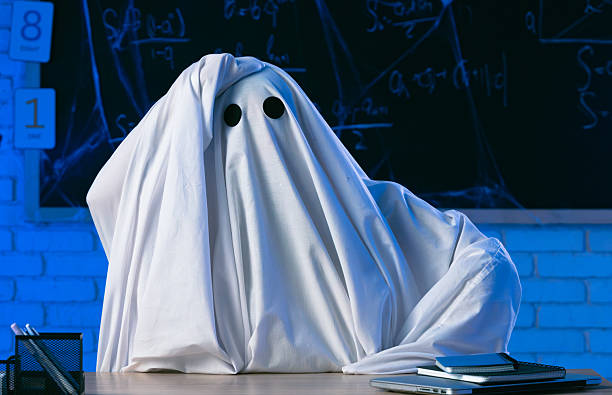 istock A man in a white ghost sheet sits at a table in a blue-lit room and clutches his head in despair 2237085547