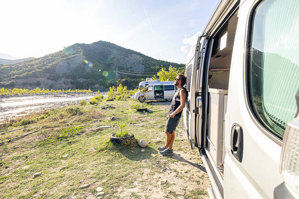 istock Man Relaxing Outside Camper Van by River 2237085567
