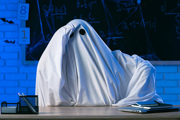 istock A man in a white ghost sheet sits at a table in a blue-lit room and clutches his head in despair 2237085665