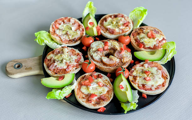 Mini Bagel Pizzas with Fresh Avocado, Brie, Ham, Cheddar and Cherry Tomatoes on Black Tray, Wooden Board
