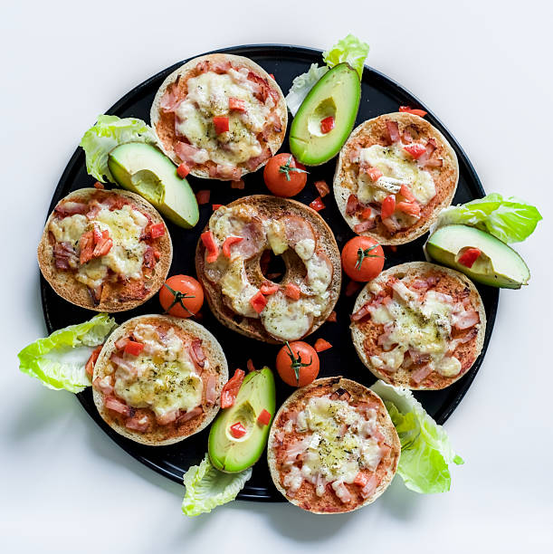 Gourmet Mini Pizzas with Avocado, Brie, Ham, Cheddar and Cherry Tomatoes on White Background
