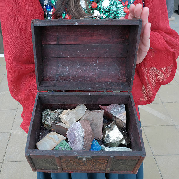 Chest with treasures, golden coins and scattered sand on table