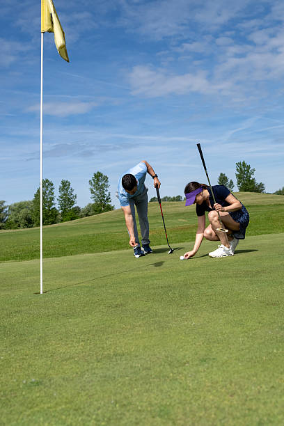 istock Two Golfers on Course, One Preparing to Putt near Yellow Flag 2237090173
