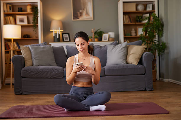 istock Woman using phone on yoga mat during home workout 2237090406