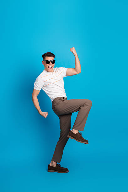 istock Energetic young man posing against a vibrant blue background, expressing excitement and happiness with dynamic gestures. 2237091905
