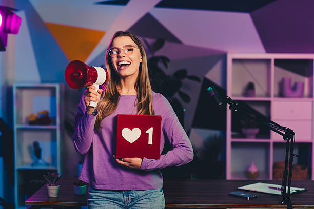 istock Young blogger with megaphone and heart prop in neon-lit creative office environment 2237094253