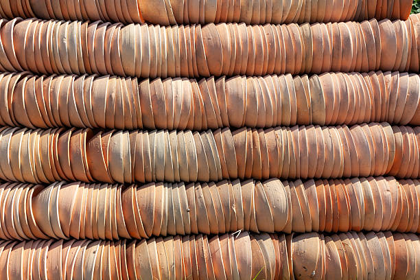Stacks of terra cotta flower  pots lay on a bench in a Cape Cod garden