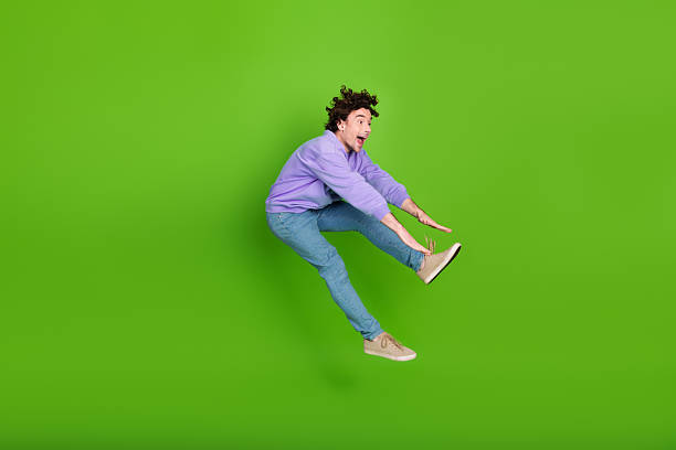istock Energetic young man in casual outfit posing dynamically against bright green background, exuding joy and liveliness 2237099651