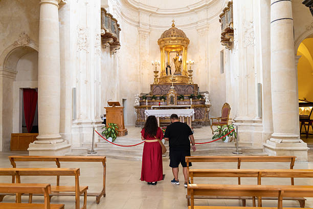 Couple praying inside historic church interior Noto, Italy, September 22, 2025
