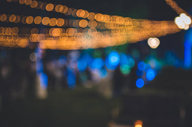 A captivating blur of string lights with warm-toned bokeh, set in an outdoor festive scene. The dreamy mix of bright blue and orange lighting creates a lively and celebratory ambience. Excellent for themes of celebration, event promotions, and atmospheric settings.