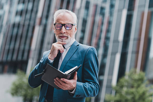 istock Confident senior businessman reviewing documents in a vibrant urban setting with a modern office building backdrop 2237103455