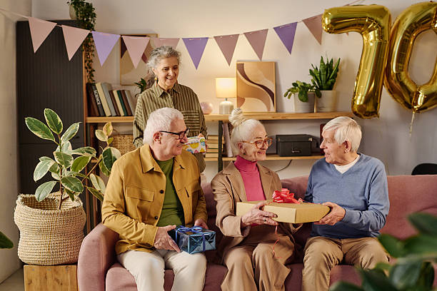 istock Senior Friends Celebrating Birthday and Exchanging Gift Boxes Indoors 2237103548