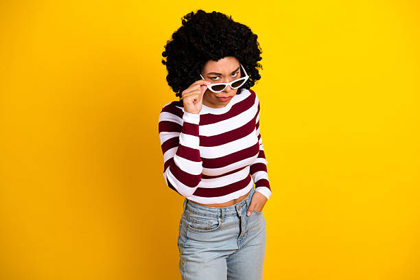 istock Confident young woman in a casual striped pullover striking a pose against a bright yellow background 2237103842