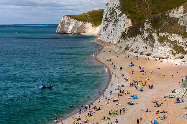 Holidaymakers swimming and sunbathing on a popular shingle beach in England