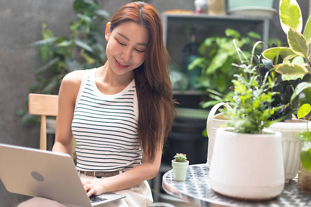 istock young  woman using a laptop  while working in a garden centre.Young people small business online sale. 2237106706