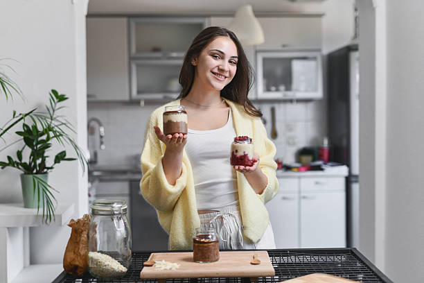 istock Cheerful Female Showing Colorful Overnight Oats Jars While Standing In Kitchen 2237108373