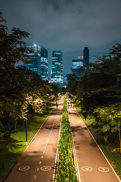 skyscrapers of night Bangkok city with Benchakitti park tracks, illuminated pathways and walkways with people walking and jogging, harmony of bustling city and nature