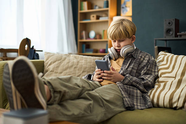 istock Boy Relaxing on Couch with Headphones and Smartphone 2237112120