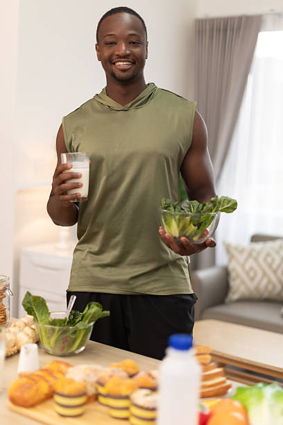 Young Black man preparing protein shake at home. Diet and healthy food.Relaxing after training.beautiful young man drink milk after done exercises.Concept of healthy lifestyle.