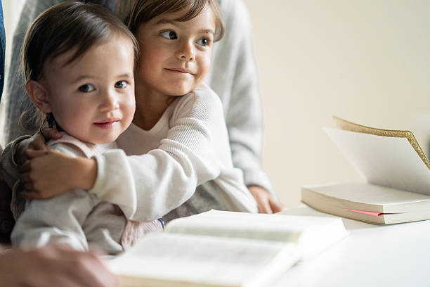 istock Two Young Sisters Share a Warm Hug While Reading Books at a Table 2237114919
