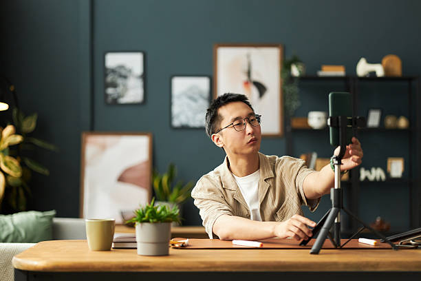 istock Young Adult Asian Man Adjusting Microphone While Recording Podcast at Desk 2237114980