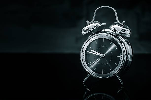 A classic vintage alarm clock with a metallic finish on a dark background, highlighting its timeless design and elegance.