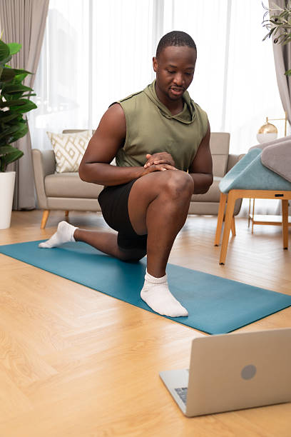 istock Smiling man working out at home.Young man doing yoga watching tutorial using laptop in apartment on mat.Training At Home And Watching Online Lessons In The Digital Tablet. 2237117862