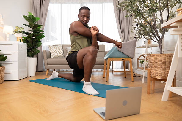 istock Smiling man working out at home.Young man doing yoga watching tutorial using laptop in apartment on mat.Training At Home And Watching Online Lessons In The Digital Tablet. 2237117925