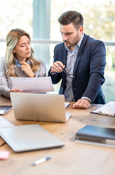 Businessman and businesswoman are commenting document while working together on project