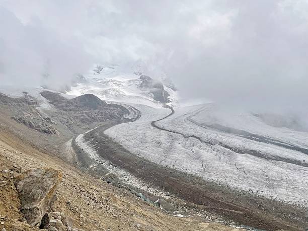 istock Glacier winding through rocky terrain under cloudy sky. 2237119346