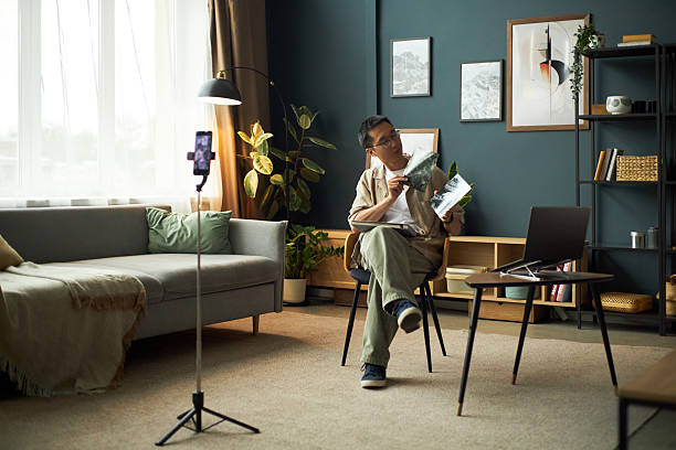 istock Middle Aged Asian Man Teaching Online Class Sitting in Modern Living Room 2237122557
