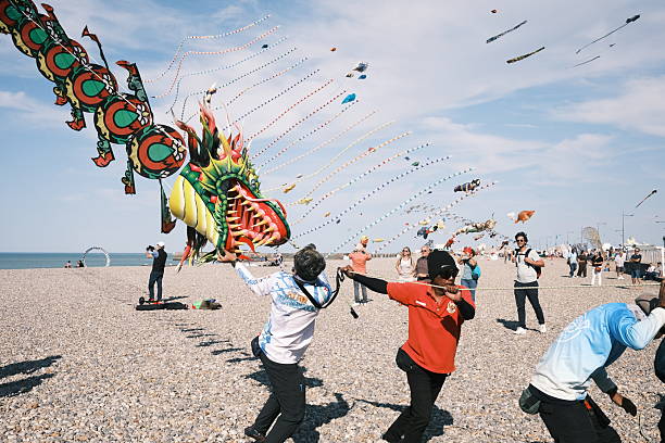 Little girl running with flying kite on the big deserted beach during a travel with family - Little girl playing with kite butterfly on sea shore in a spring sunny day