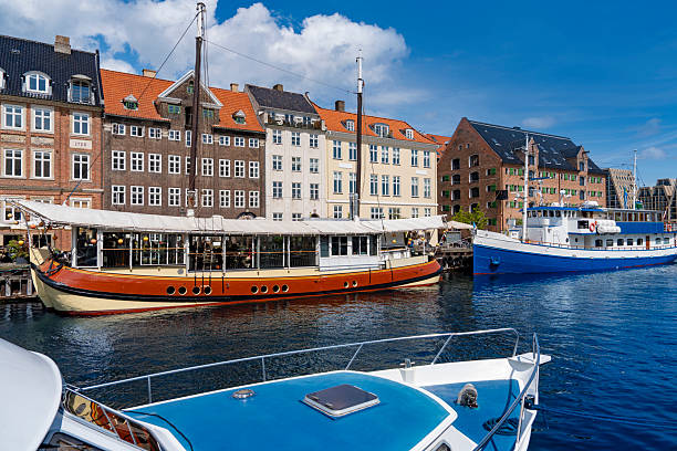 Bright summer Nyhavn harbor with colorful houses and boats reflecting in the water in Copenhagen