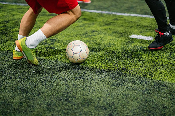 Two young men playing football in the field indoors. Close-up.