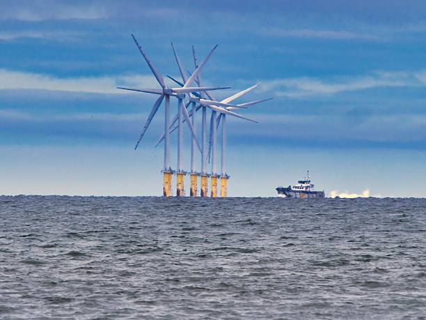 istock Offshore wind turbines and boat under cloudy sky. 2237130270