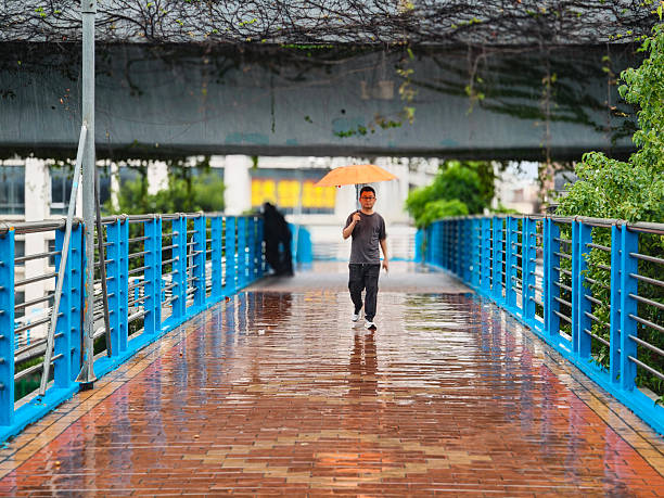 A man walking on a pedestrian overpass on a rainy day
