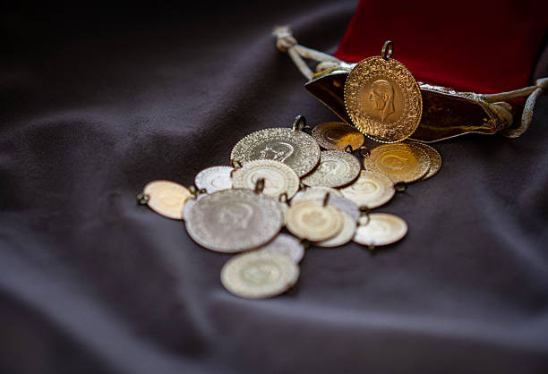 Close-up view of traditional Turkish gold coins (Republic coins) spilled from a red pouch on fabric background