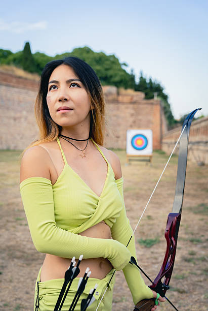 istock Young woman concentrating on archery target, holding bow and arrows outdoors, practicing her aim and focus 2237141084