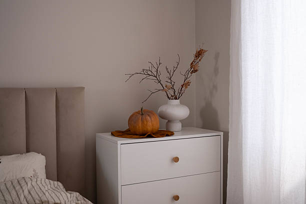istock A beautifully serene bedroom scene adorned with cozy autumn decor, featuring a charming pumpkin and dried branches. 2237141958