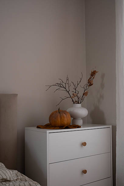 istock A beautifully serene bedroom scene adorned with cozy autumn decor, featuring a charming pumpkin and dried branches. 2237142114