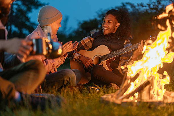 istock Man playing the guitar next to the campfire 2237144446