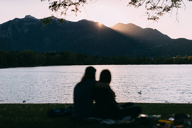 istock A couple enjoys sitting by the tranquil lake while watching the sunset 2237148143