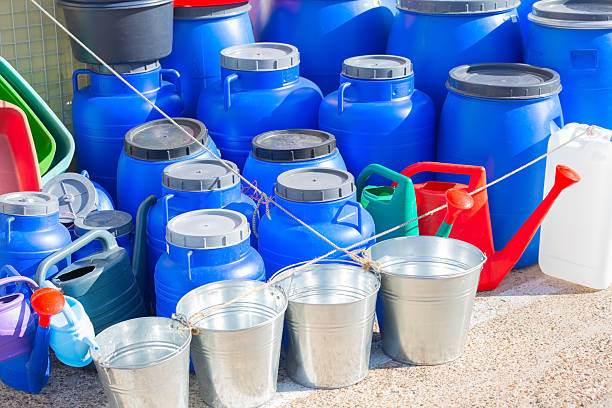 Blue plastic barrels, buckets, and watering cans displaying water storage and gardening equipment