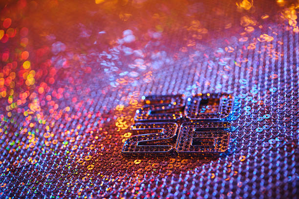 Vertical 2026 typography shines on a vivid sequin background, glowing with multicolored festive lights. A luxurious still life concept celebrating the arrival of the New Year in a glamorous, colorful, and joyful holiday atmosphere.